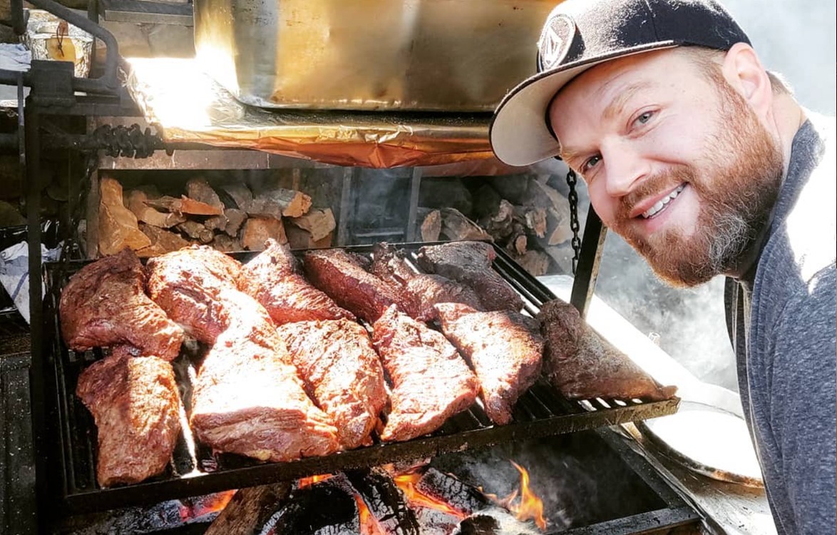 Steaks searing over open fire on a wood-fired grill